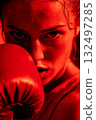 A woman wearing a red boxing glove is shown in a close up 132497285