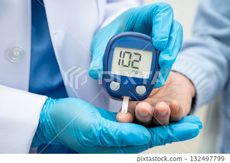 Asian doctor using digital glucose meter for check sample blood sugar level to treatment diabetes. Asian doctor using digital glucose meter for check sample blood sugar level to treatment diabetes. 132497799