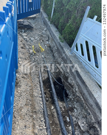 Blue fence is behind a hole in the ground 132497974