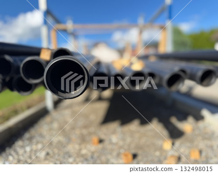 Pile of pipes with one of them being black and having a hole in it Pile of pipes with one of them being black and having a hole in it 132498015