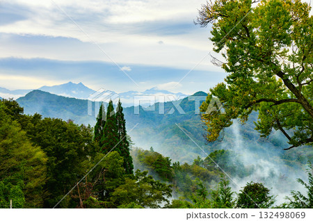 Smoke from field burning and the Ushiro-Tateyama mountain range in the background [Ooka, Nagano City] 132498069