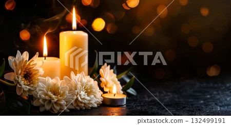 Elegant arrangement of lit candles surrounded by white flowers on dark background, creating a warm and inviting atmosphere for Halloween celebrations 132499191