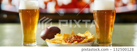 Super Bowl game party, glass of beer and plate of chips with salsa next to television screen Super Bowl game party, glass of beer and plate of chips with salsa next to television screen 132500128