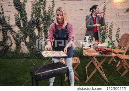 Enjoying a colorful evening barbecue with friends in a charming garden Enjoying a colorful evening barbecue with friends in a charming garden 132500355