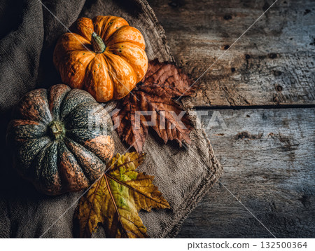Colorful pumpkins and autumn leaves arranged on rustic wooden surface with natural textures 132500364