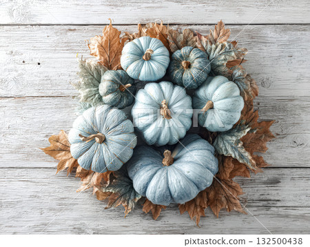Blue pumpkins arranged with autumn leaves on a rustic wooden surface for seasonal decor 132500438
