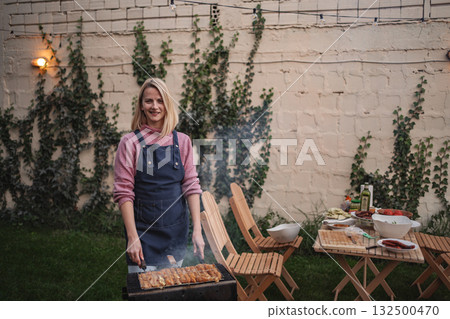 Enjoying a backyard barbecue with friends during a sunny afternoon 132500470