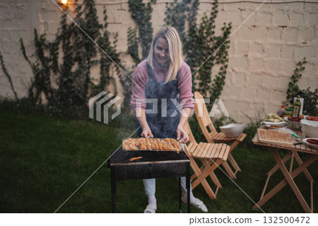 Grilling delicious skewers in a cozy outdoor backyard setting at dusk Grilling delicious skewers in a cozy outdoor backyard setting at dusk 132500472