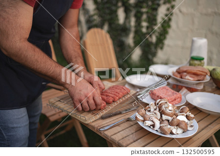 Grilling vibrant sausages and fresh mushrooms in a backyard gathering 132500595