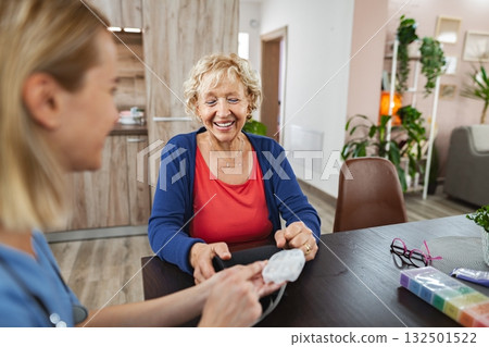 Cheerful interaction between caregiver and elderly woman in bright living space 132501522