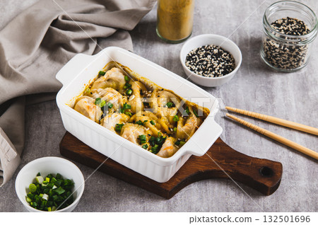 Dumpling Bake in coconut curry sauce with sesame seeds in a baking dish on the table 132501696