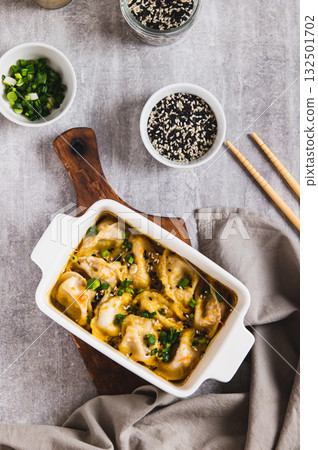 Dumpling Bake in coconut curry sauce with sesame seeds in a baking dish top and vertical view 132501702