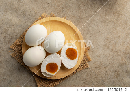 Salted eggs in wooden plate.a preserved food, traditionally made by curing duck or chicken eggs in brine.popular delicacy in many Asian cuisines.Top view. Salted eggs in wooden plate.a preserved food, traditionally made by curing duck or chicken eggs in brine.popular delicacy in many Asian cuisines.Top view. 132501742