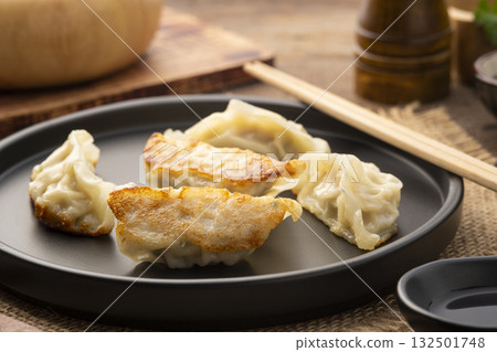 gyoza,Japanese style grilled dumplings with pork and vegetables on black plate 132501748