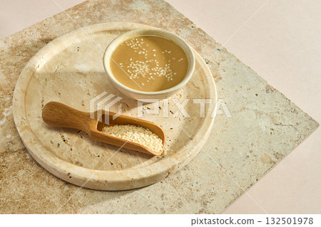 Sesame Tahini Bowl. A bowl of creamy tahini with sesame seeds on a rustic travertine surface. Sesame Tahini Bowl. A bowl of creamy tahini with sesame seeds on a rustic travertine surface. 132501978
