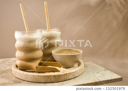 Sesame Tahini Latte Delight. Creamy sesame paste and iced tahini lattes on rustic travertine surface. 132501979