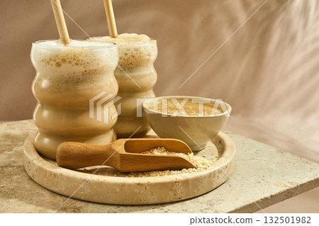 Sesame Tahini Latte Delight. Creamy sesame paste and iced tahini lattes on rustic travertine surface. Sesame Tahini Latte Delight. Creamy sesame paste and iced tahini lattes on rustic travertine surface. 132501982