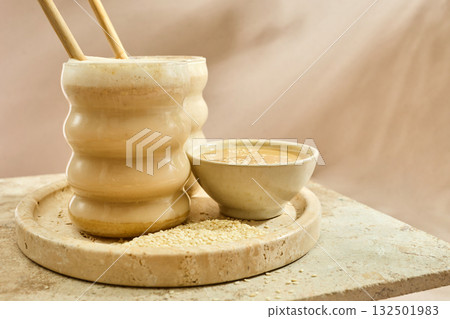 Sesame Tahini Latte Delight. Creamy sesame paste and iced tahini lattes on rustic travertine surface. 132501983