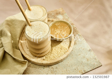 Sesame Tahini Latte Delight. Creamy sesame paste and iced tahini lattes on rustic travertine surface. Sesame Tahini Latte Delight. Creamy sesame paste and iced tahini lattes on rustic travertine surface. 132501987