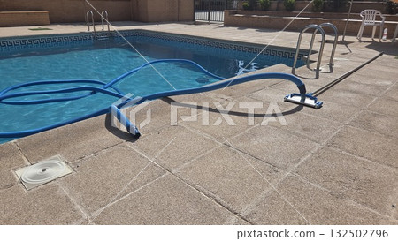 Summer pool maintenance scene with cleaning equipment and clear blue water Summer pool maintenance scene with cleaning equipment and clear blue water 132502796