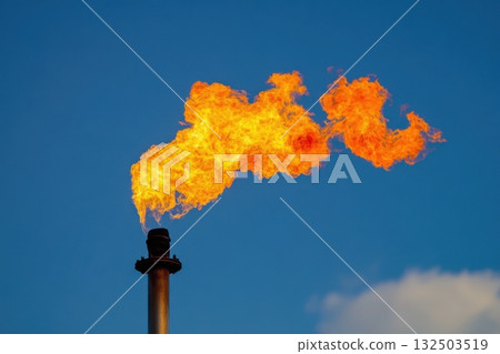 Industrial gas flare burning against clear blue sky, close-up of fire plume Industrial gas flare burning against clear blue sky, close-up of fire plume 132503519