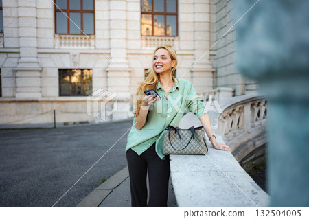 Young woman smiling holding smartphone traveling in Vienna 132504005