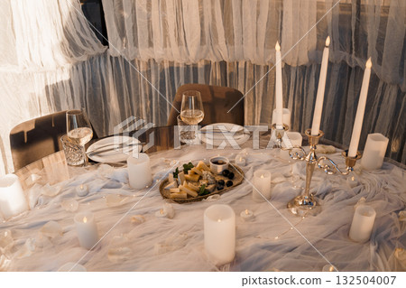 Romantic Dinner Setting with Candles, Wine Glasses, and Charcuterie Board Warm Intimate Mood, Soft Lighting, Elegant Table Decor, White and Gold Tones Romantic Dinner Setting with Candles, Wine Glasses, and Charcuterie Board Warm Intimate Mood, Soft Lighting, Elegant Table Decor, White and Gold Tones 132504007