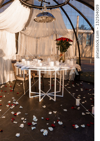 Romantic Dinner Setup in Greenhouse: Rose Petals, Candles, White Drapes and Table for Two  Love, Valentine's Day, Elegant Mood 132504009