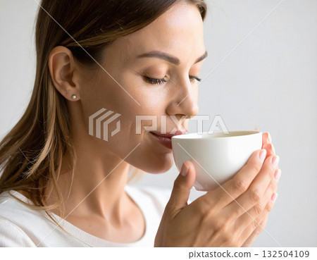 Woman enjoying morning tea with gentle satisfied expression Woman enjoying morning tea with gentle satisfied expression 132504109