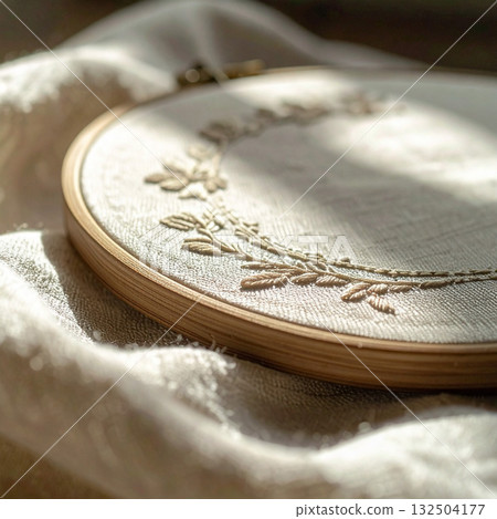 繡花框中手工刺繡的植物圖案沐浴在自然光和亞麻布的溫暖質感中 132504177