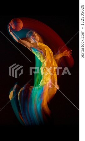 Basketball player in yellow uniform making dynamic jump with colorful motion trail Basketball player in yellow uniform making dynamic jump with colorful motion trail 132505029