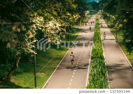 skyscrapers of night Bangkok city with Benchakitti park tracks, illuminated pathways and walkways with people walking and jogging, harmony of bustling city and nature 132505194