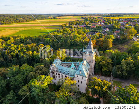 Stranov Castle stands proudly in Central Bohemia, surrounded by lush greenery and open fields. This aerial view captures the castle's unique architecture and scenic landscape during a sunny day. Stranov Castle stands proudly in Central Bohemia, surrounded by lush greenery and open fields. This aerial view captures the castle's unique architecture and scenic landscape during a sunny day. 132506271
