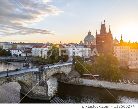 The sun sets over the historic Old Town Bridge Tower located by Charles Bridge in Prague. The river reflects warm colors as the day transitions to evening, highlighting the charming architecture. The sun sets over the historic Old Town Bridge Tower located by Charles Bridge in Prague. The river reflects warm colors as the day transitions to evening, highlighting the charming architecture. 132506274