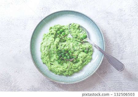 Delicious green pea puree served in a stylish bowl garnished with fresh peas and microgreens for a healthy meal Delicious green pea puree served in a stylish bowl garnished with fresh peas and microgreens for a healthy meal 132506503