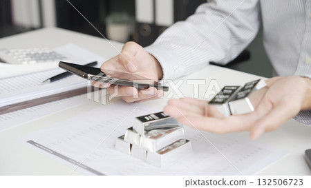 Silver Trading Businessman invest in trading silver, calculating price and monitoring online using smartphone. Silver Trading Businessman invest in trading silver, calculating price and monitoring online using smartphone. 132506723