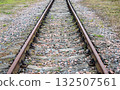 Perspective view of an empty, straight railway line disappearing into the horizon on a cloudy autumn day. 132507561
