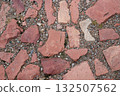 Ancient road made of red granite tiles, a close-up view from above. Old brick cobblestone tiles street 132507562