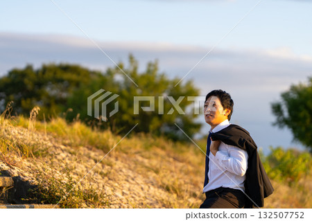 A businessman walking up a slope in the setting sun—towards the light of hope A businessman walking up a slope in the setting sun—towards the light of hope 132507752