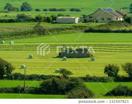 Idyllic rural farmland shows green fields and houses in scenic West Cork, Ireland during a sunny day. Idyllic rural farmland shows green fields and houses in scenic West Cork, Ireland during a sunny day. 132507921