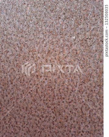 The surface of a rusty iron sheet reveals a detailed texture, marked by patterns of age and wear. Natural light highlights the reddish-brown tones, emphasizing the metal's history and transformation. The surface of a rusty iron sheet reveals a detailed texture, marked by patterns of age and wear. Natural light highlights the reddish-brown tones, emphasizing the metal's history and transformation. 132508035