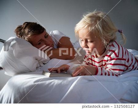Little girl reading a book to her sick mother in bed. a child help and the joy of parenthood 132508127