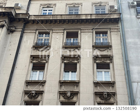 Historic stone building facade with sculpted ornaments and windows. Classical architecture, European heritage, and urban elegance in city center. 132508190