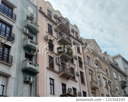 Historic residential architecture with balconies and air conditioners under cloudy sky. Urban texture, lifestyle, and heritage building facade in European city. Historic residential architecture with balconies and air conditioners under cloudy sky. Urban texture, lifestyle, and heritage building facade in European city. 132508193