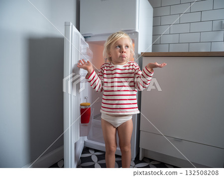 Little girl looking into an empty fridge and spreading her arms in confusion 132508208