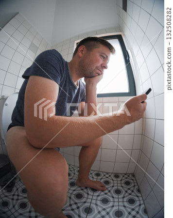 Man sitting on the toilet using his smartphone, bad habit and internet addiction concept Man sitting on the toilet using his smartphone, bad habit and internet addiction concept 132508282