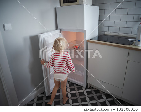 Little hungry girl looking into an empty refrigerator at home, no food concept 132508310