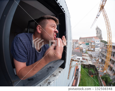 Man angrily staring at a noisy construction site outside his apartment window  132508348