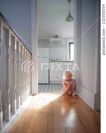 Little girl sitting alone on the floor at home, feeling scared while waiting for her parents Little girl sitting alone on the floor at home, feeling scared while waiting for her parents 132508354