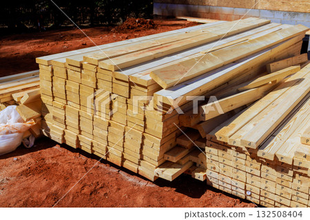 Wooden beams, planks arranged in piles await use for building construction Wooden beams, planks arranged in piles await use for building construction 132508404